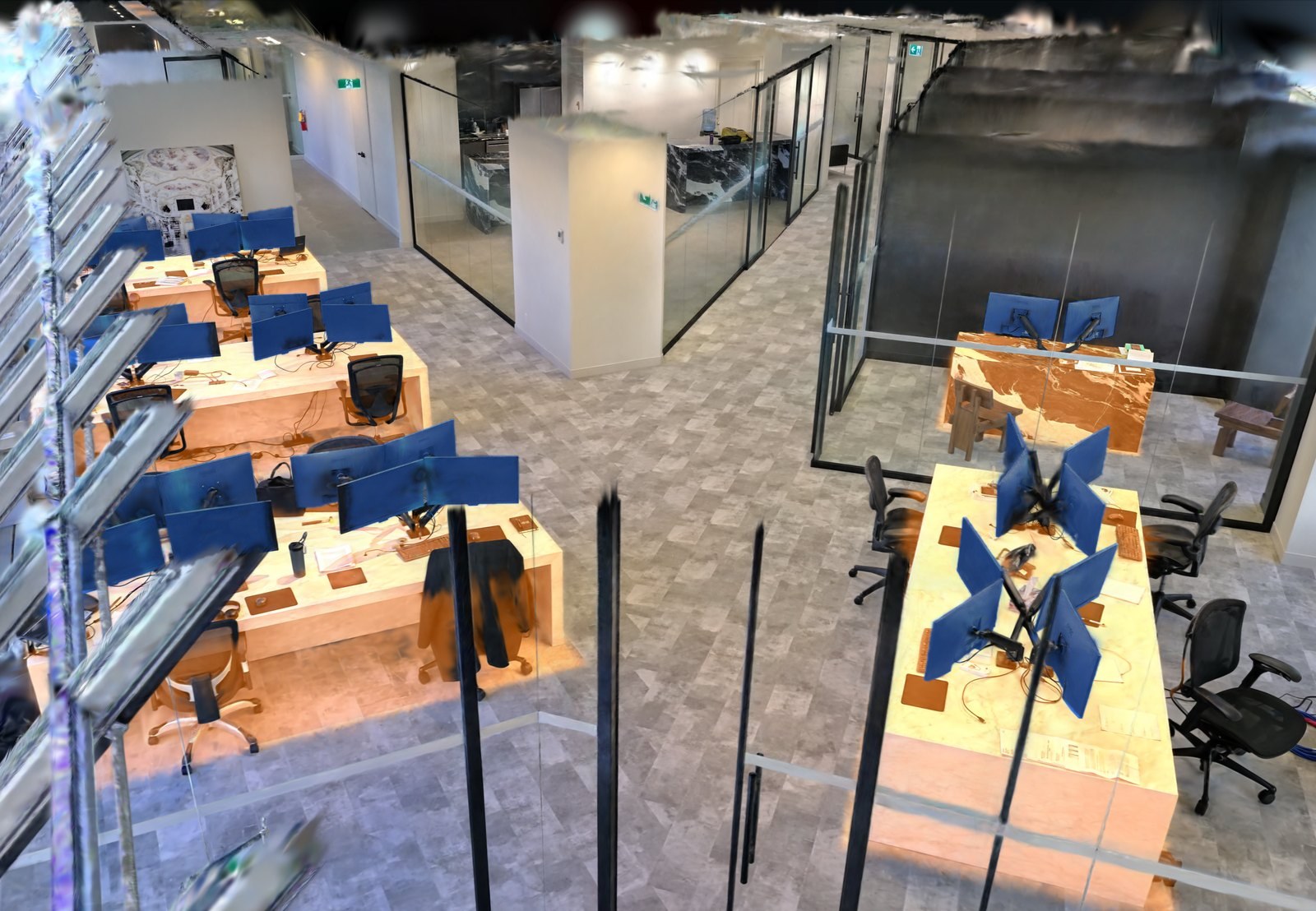 Overhead view of the office splat with desks lit up and one monitor at a time glowing bright blue