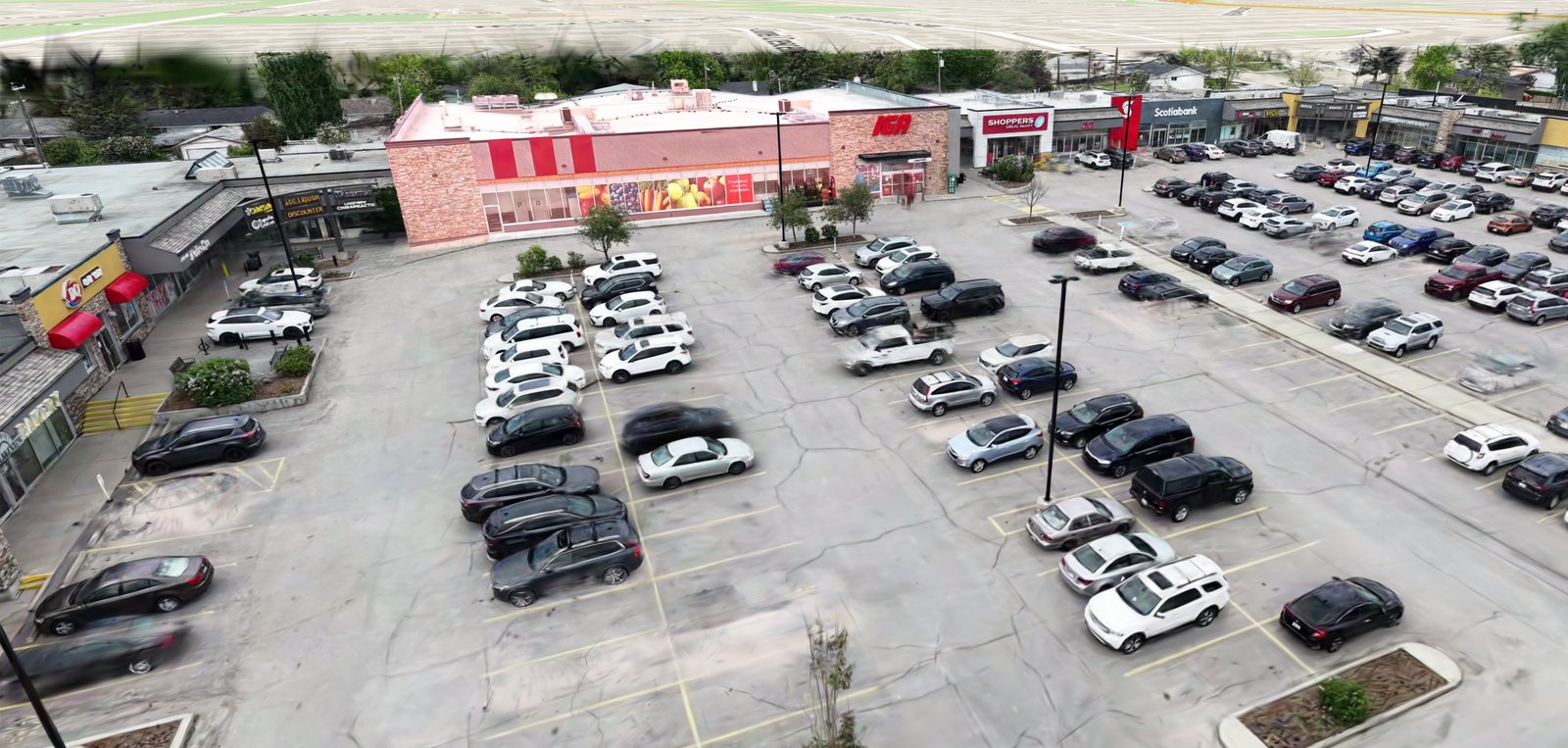 Aerial splat of a shopping plaza with storefront signs and a parking lot