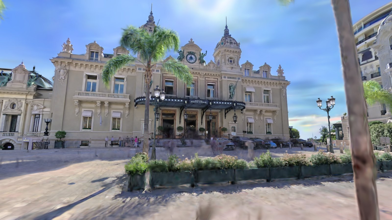 Splat of the Casino de Monte-Carlo facade behind palm trees and a planted border on the Place du Casino